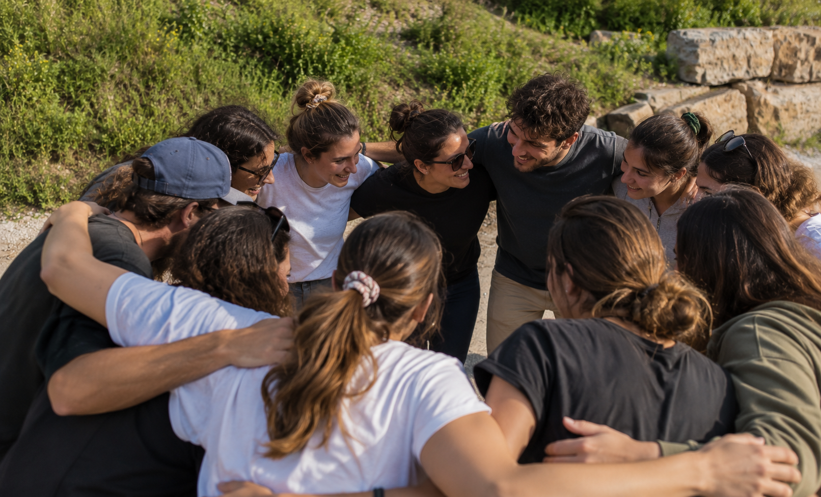 Grup formant una rotllana abraçats durant l’activitat de cohesió