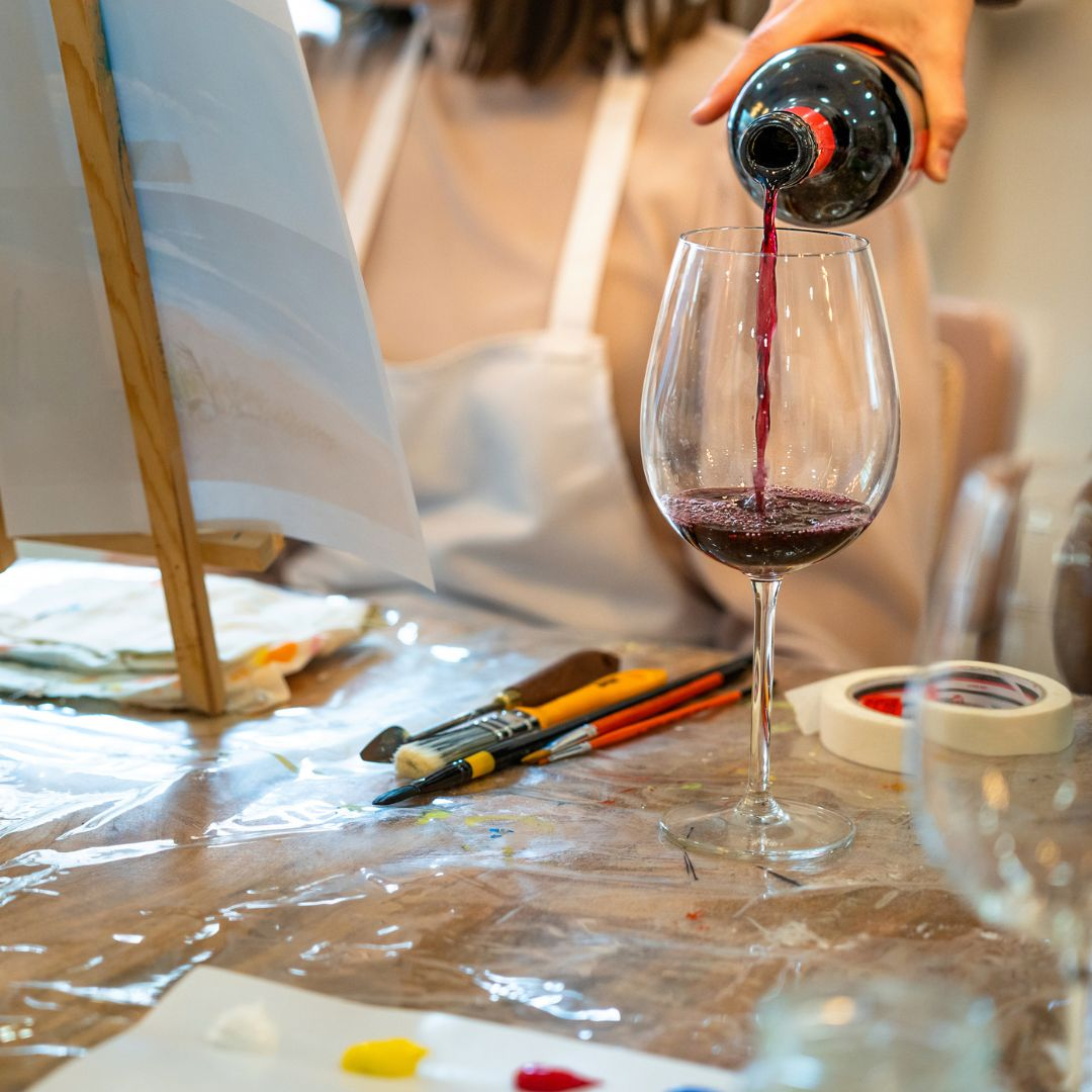 Vi servint-se al costat d’un cavallet i pinzells durant Pintura i vi